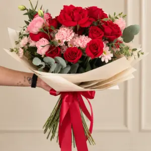 Ramo Blush con flores rojas y rosadas y envoltura clara, Dos Gardenias.