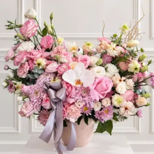 Arreglo Aurora con flores rosas, blancas y lavanda en base decorativa.
