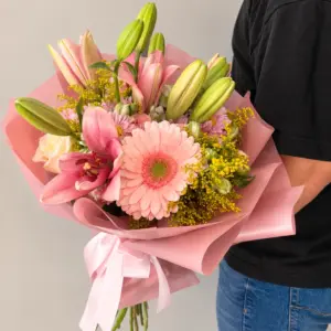 Ramo Ilusión con lirios, gerberas y flores rosadas, envuelto en papel rosa.